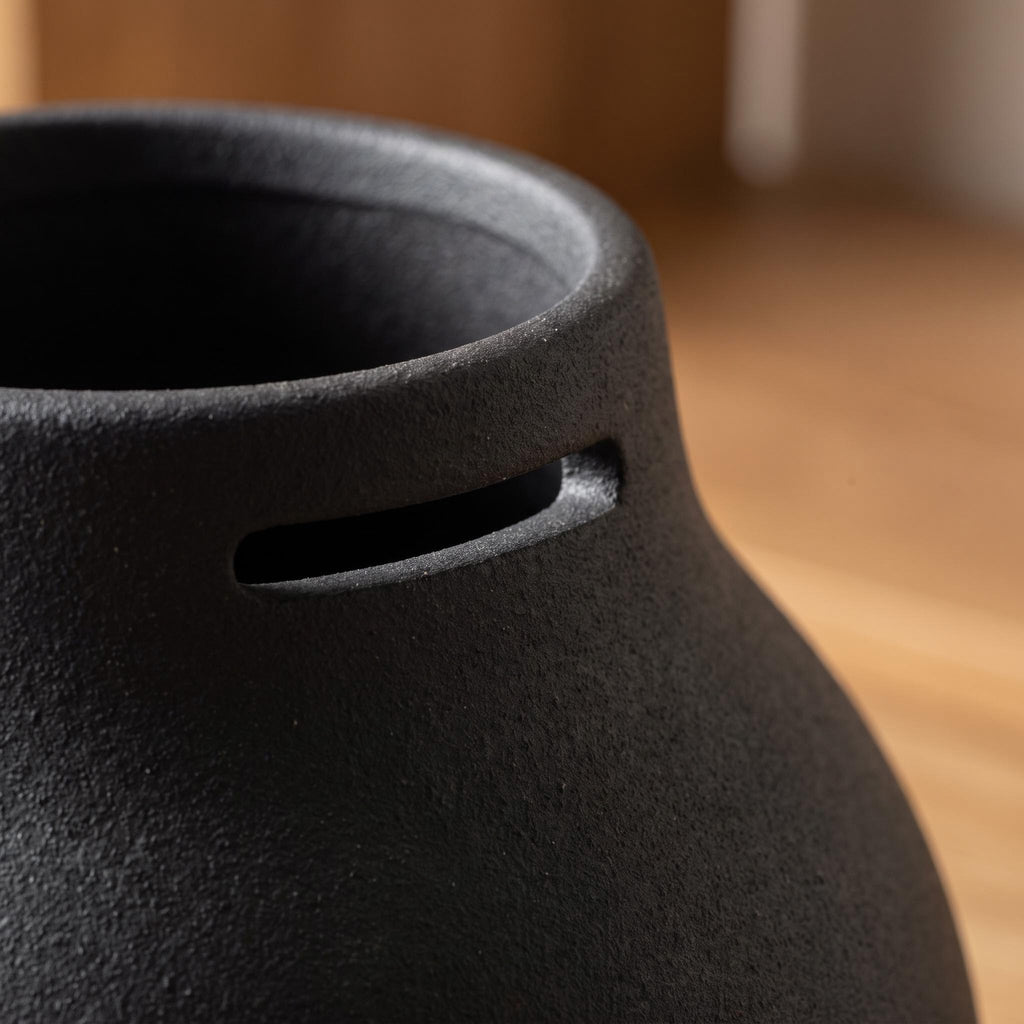 Close-up of one narrow slot opening and the matte black ceramic of the Doven vase
