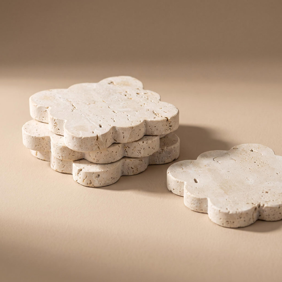 Pietra set of four flower-shaped travertine coasters on a warm neutral background