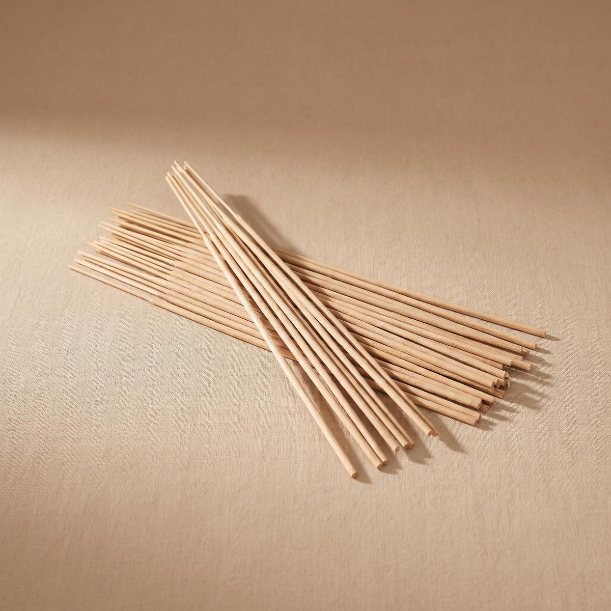 Sandal undyed sandalwood incense sticks fanned out on a warm neutral background