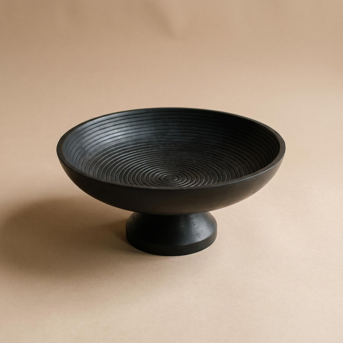 Korren matte black footed bowl with concentric rings inside, empty, on a warm neutral background