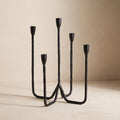 Kebro five-arm forged iron candelabra, unlit, on a warm neutral background
