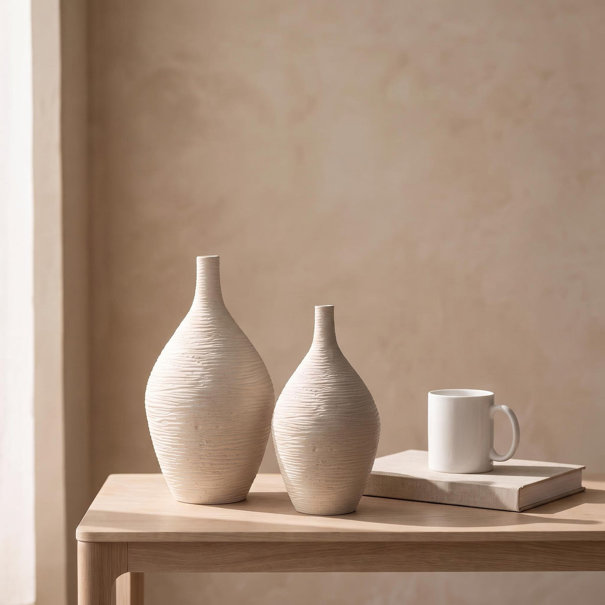 Tall and short Esbel vases next to a coffee mug and a book to show their real size