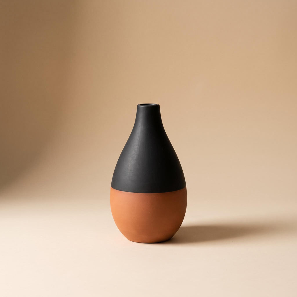 Terra two-tone stoneware vase, terracotta below and matte black above, on a warm neutral background