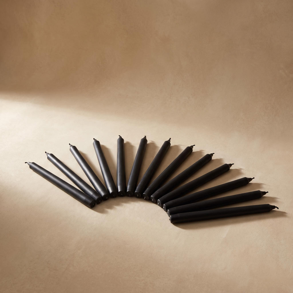 Cono black taper candles fanned out on a warm neutral background