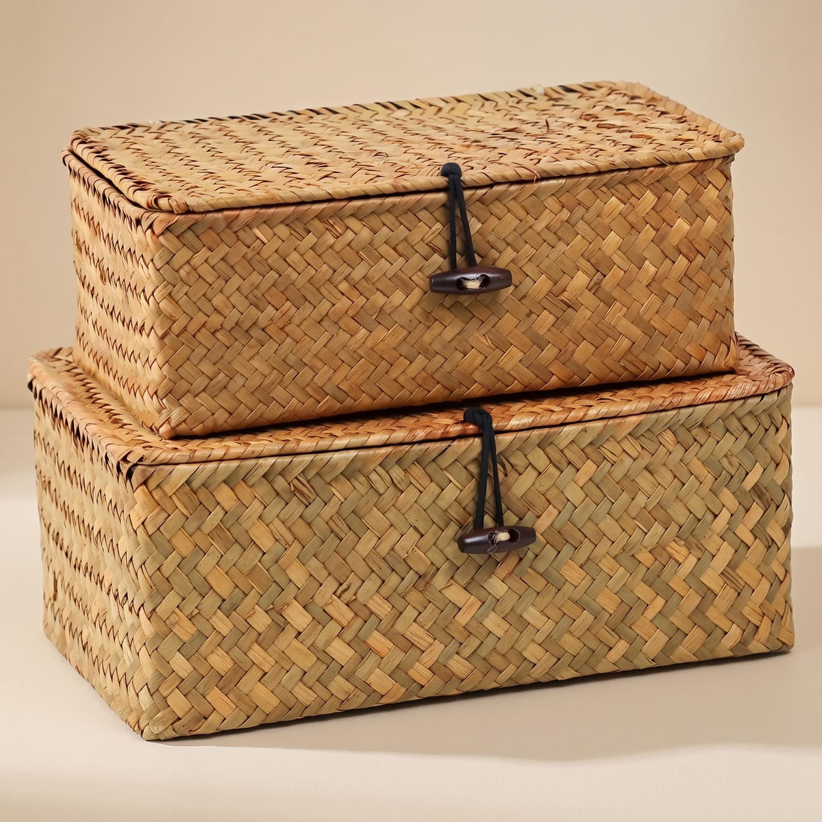 Ostria pair of lidded seagrass baskets stacked on a warm neutral background