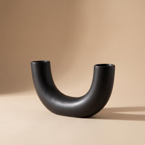 Doven matte black U-shaped ceramic vase, empty, on a warm neutral background
