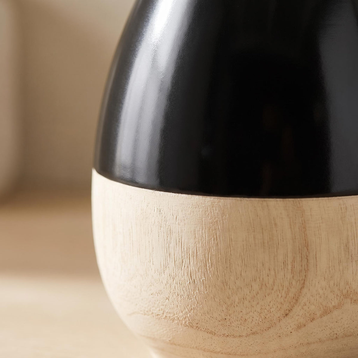 Close-up of the line where glossy black meets the pale wood-look band on the Terra vase
