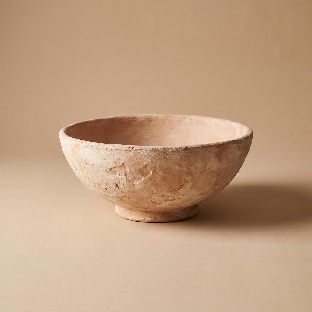 Cálida unglazed clay bowl on a low foot, empty, on a warm neutral background