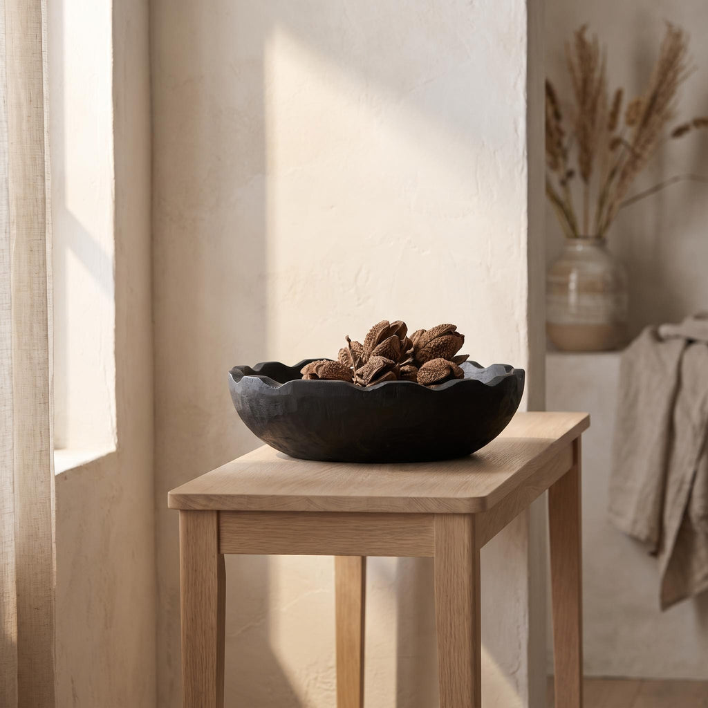 Ondel bowl on a pale oak console holding dried seed pods