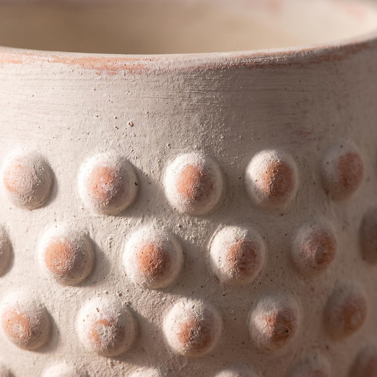 Close-up of the hobnail bumps and terracotta blush under the white limewash