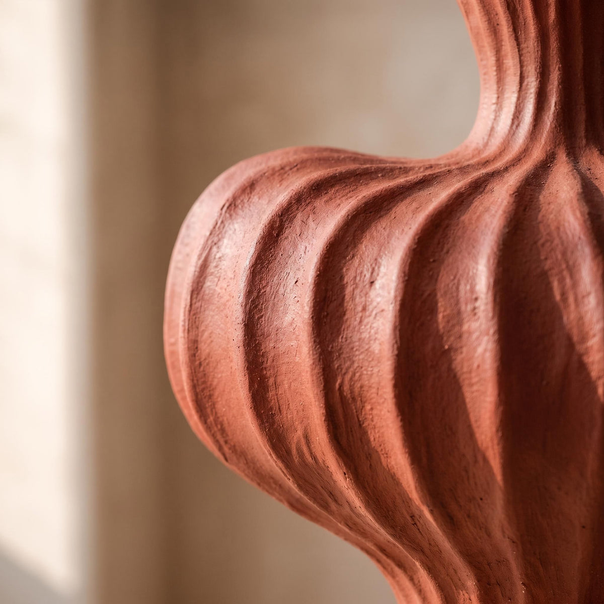 Close-up of the deep ribs and matte brick-red surface of the Teja vase