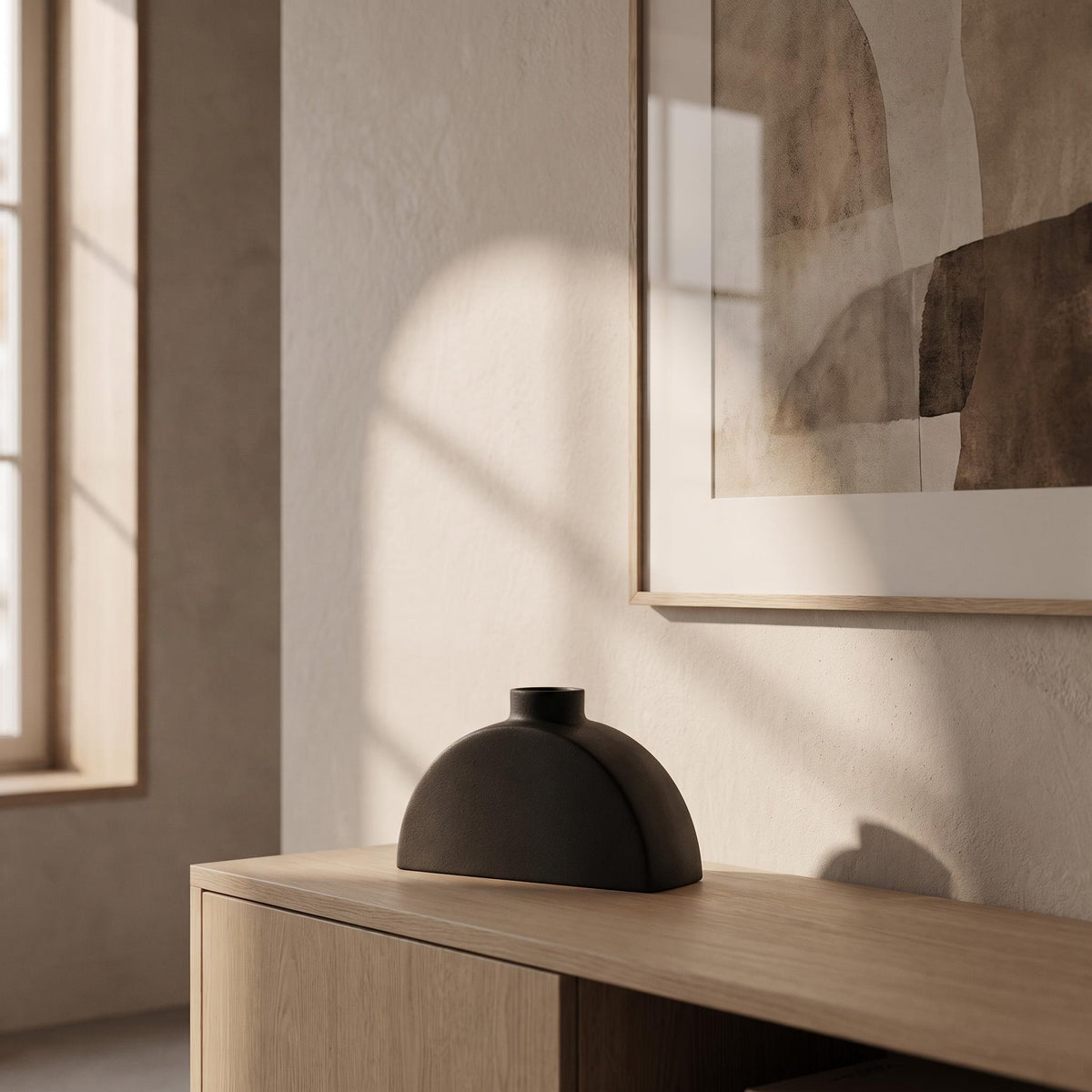 Doven vase empty on a console under a framed picture in afternoon light