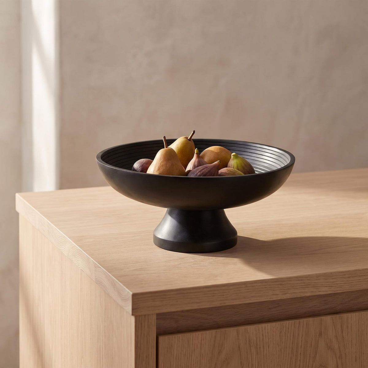 Korren bowl on a kitchen island holding pears and figs