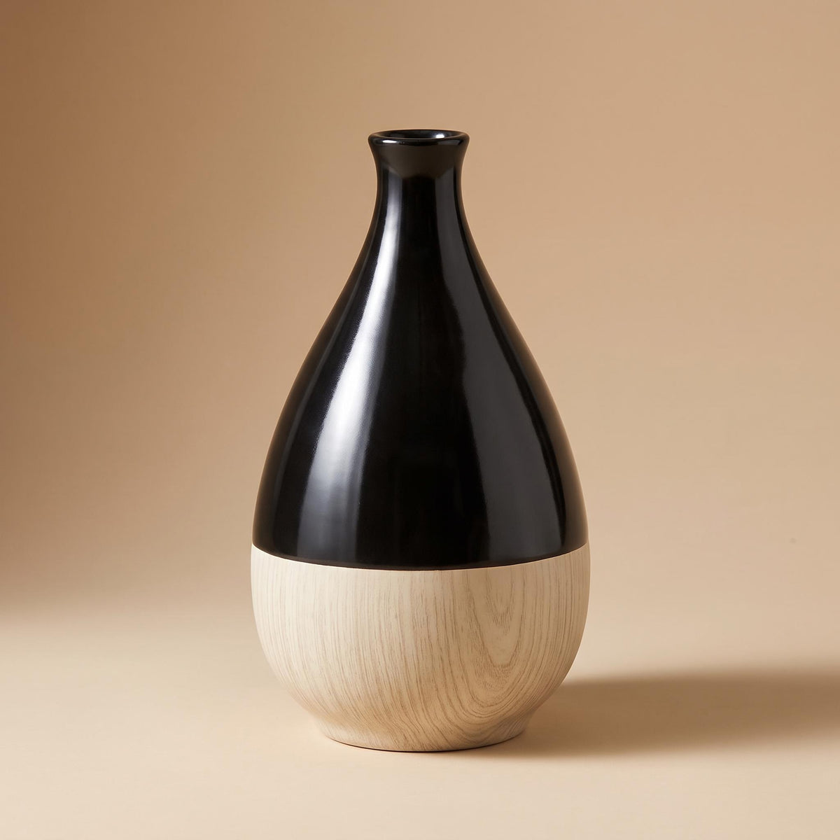 Terra bottle vase, glossy black above and pale wood-look below, on a warm neutral background