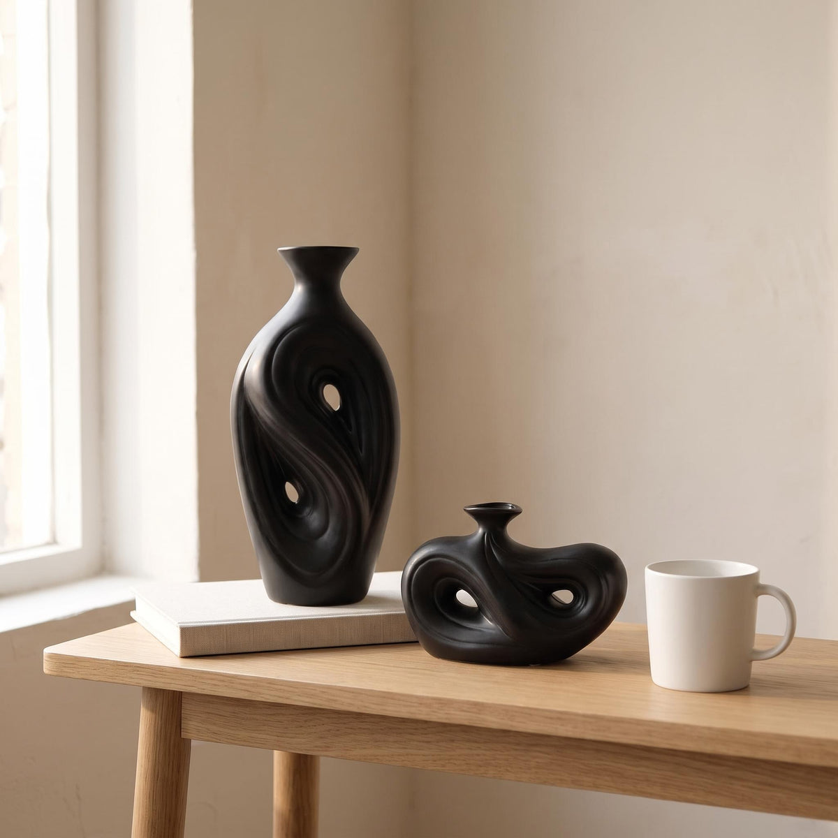 Tall and low Umbra vases next to a coffee mug and a book to show their real size