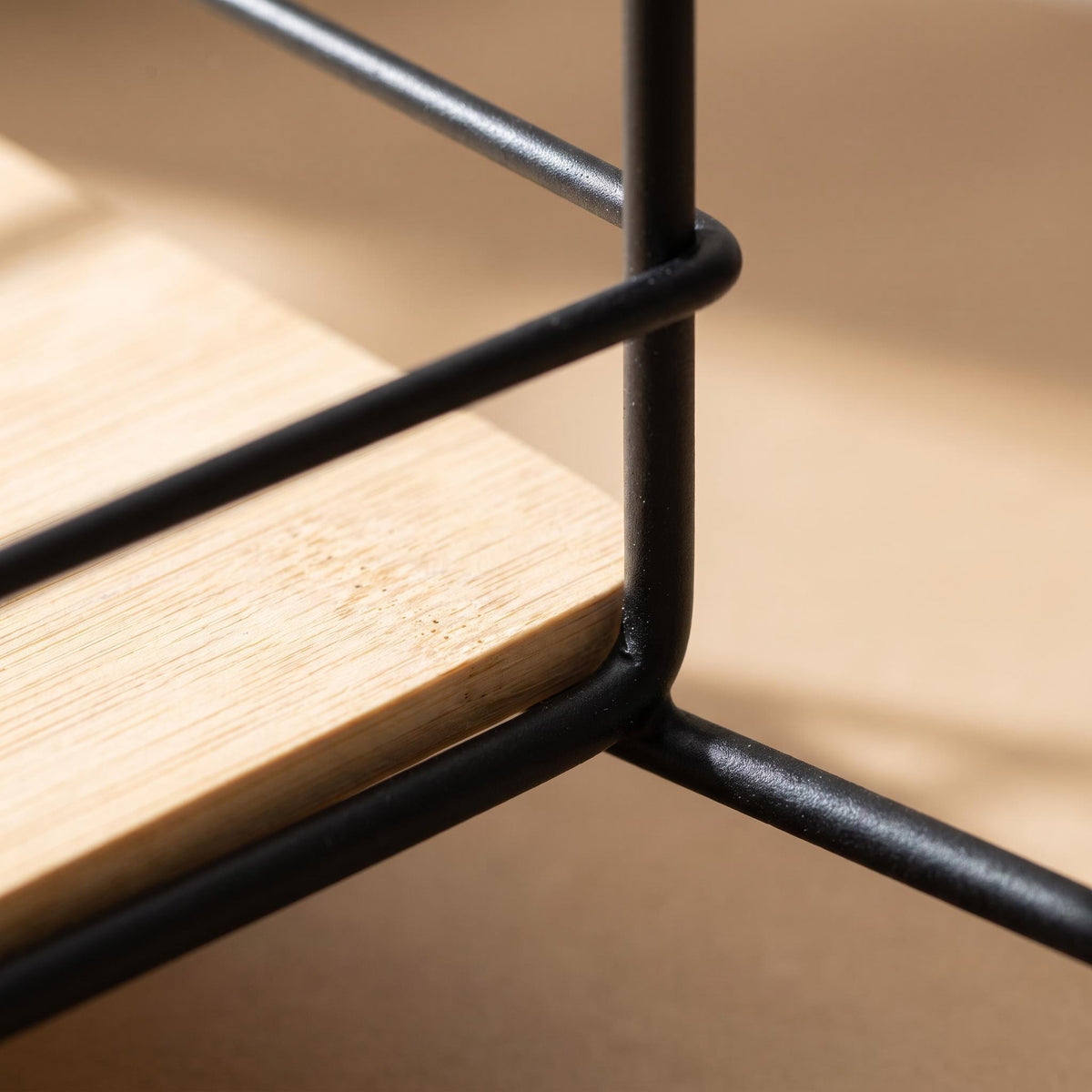 Close-up of the black rods meeting the bamboo board on the Sável tray