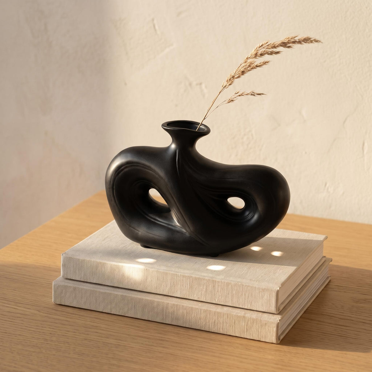 Umbra low black ceramic vase on a stack of linen books