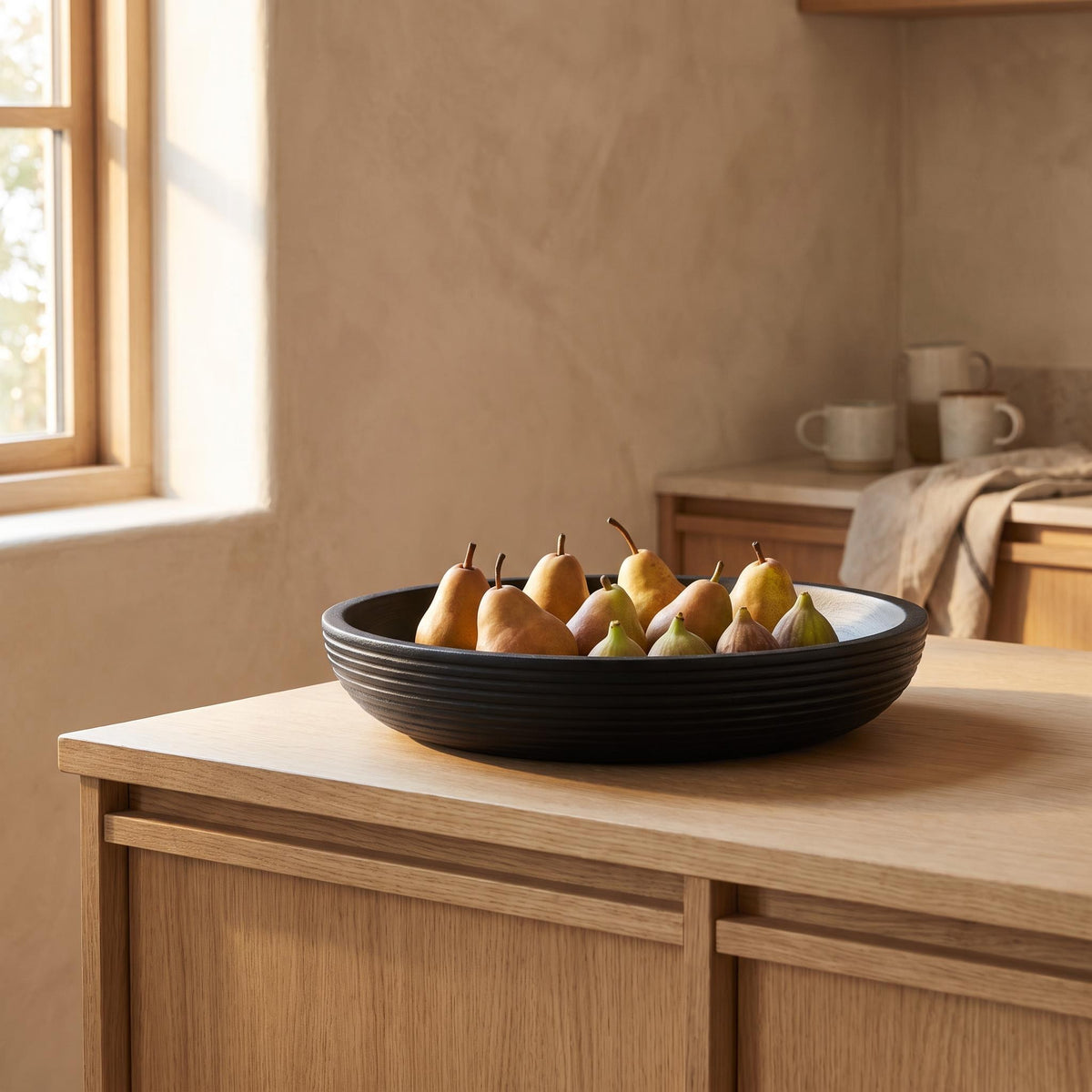Korren bowl on a kitchen island holding pears and figs in a single layer