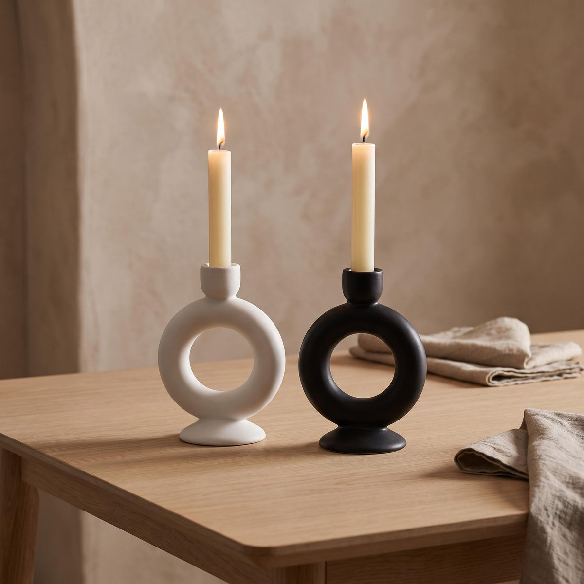 Anel white and black holders on a dining table with two lit cream tapers