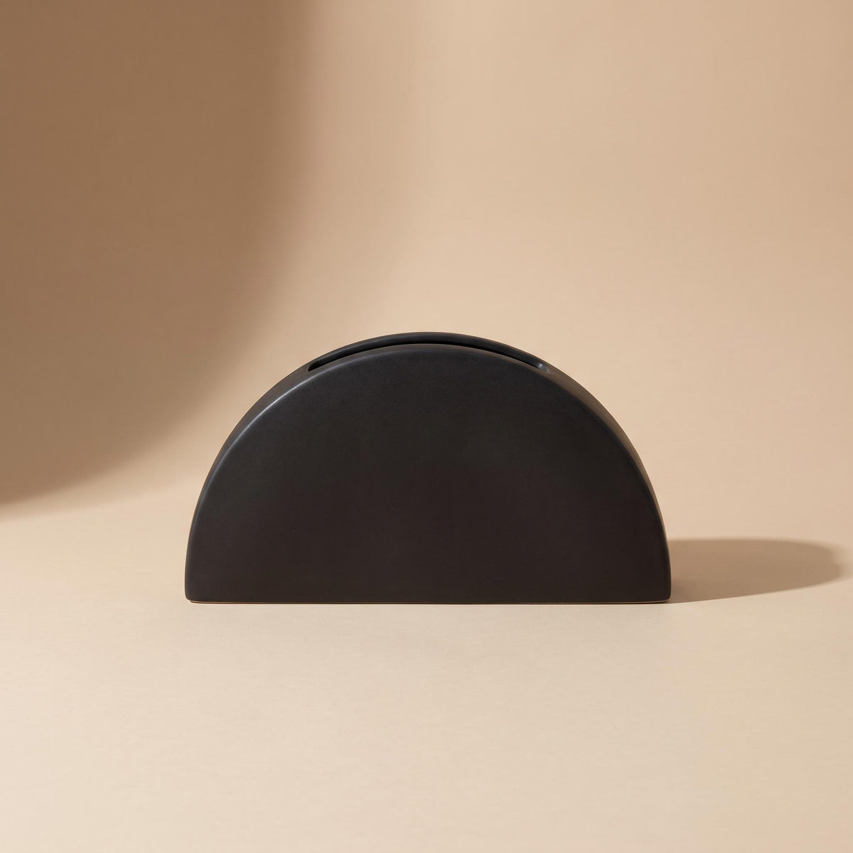 Doven matte black half-circle stoneware vase, empty, on a warm neutral background