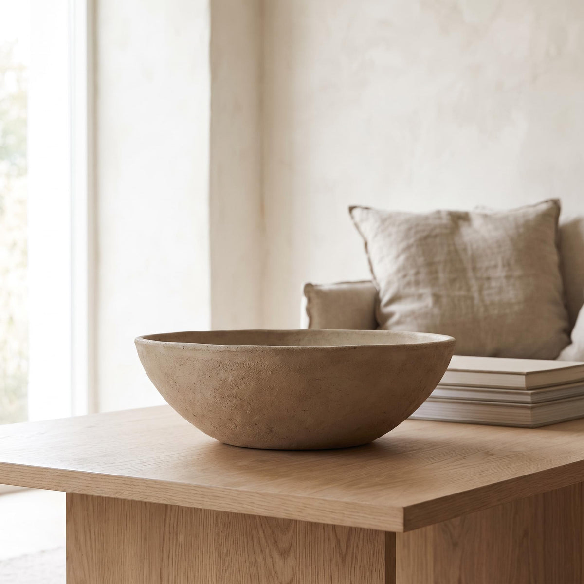 Cálida bowl empty on a pale oak coffee table beside a stack of books