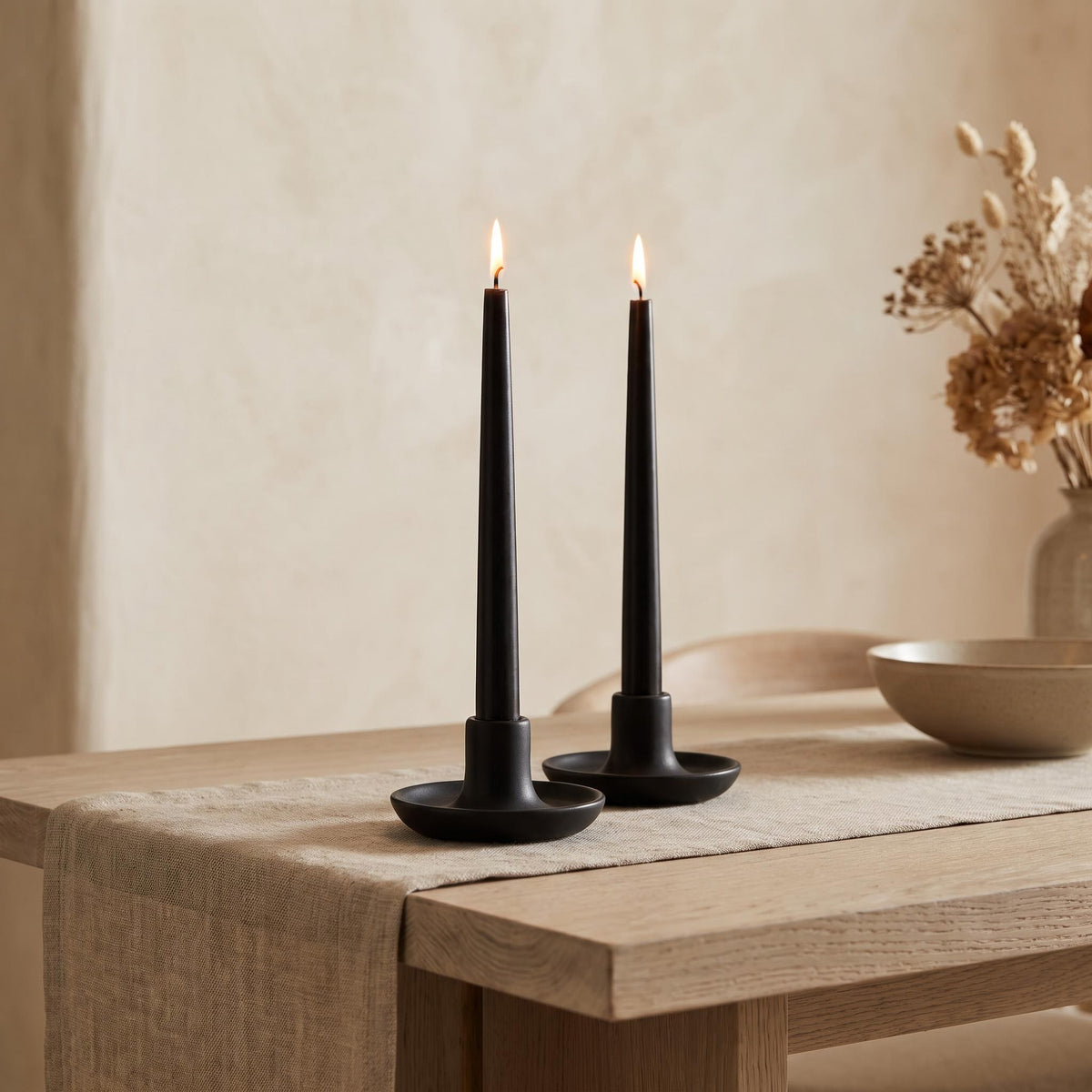 Cono black tapers burning in matte black holders on a dining table