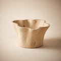 Aurebo carved wooden bowl with an irregular rim that rises and falls, empty, on a warm neutral background