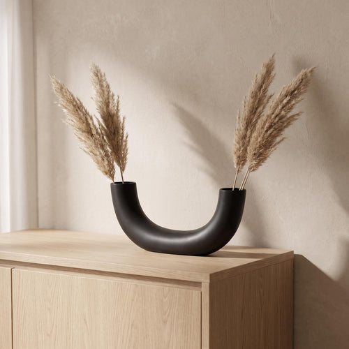 Doven vase on a pale oak sideboard with dried pampas rising from both open ends