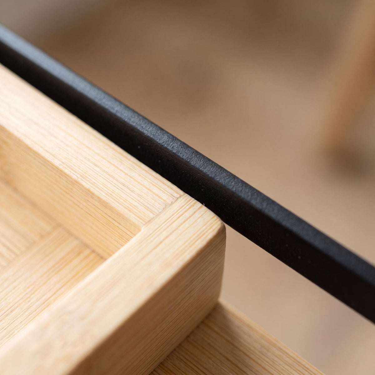 Close-up of the bamboo grain meeting the black steel rail of the Sável tray