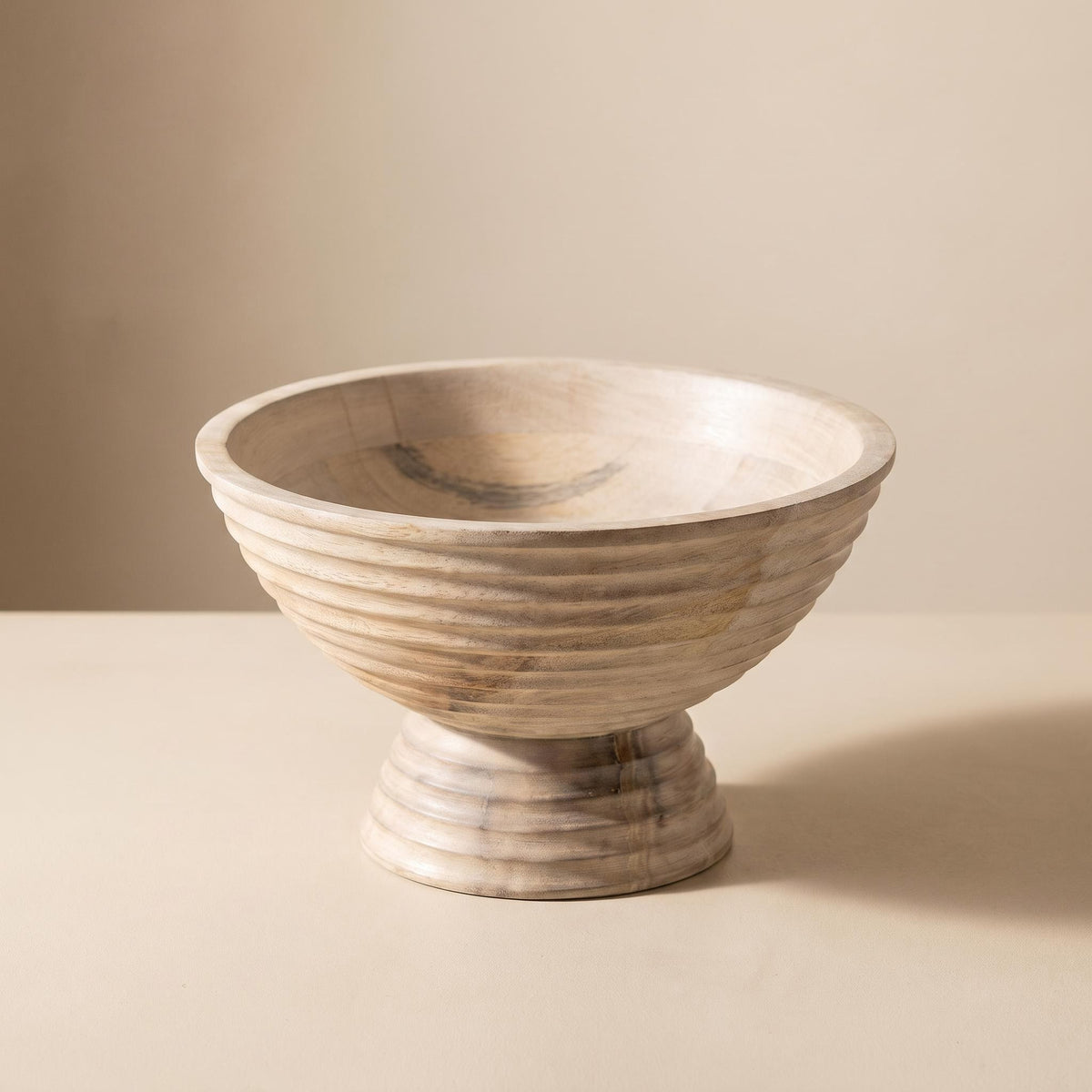 Ormu ridged mango wood footed bowl, empty, on a warm neutral background