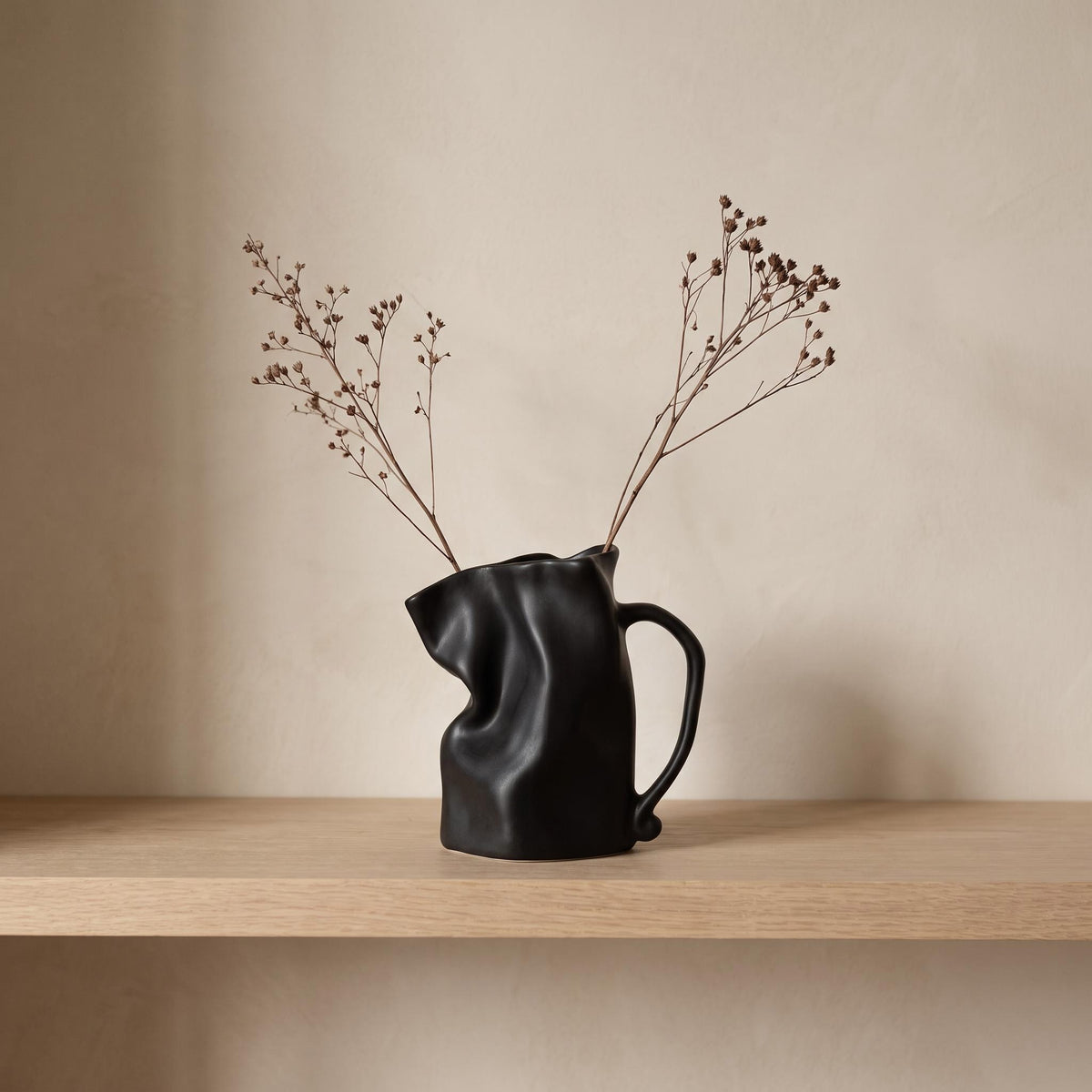 Plica crumpled ceramic jug vase in black with dried stems