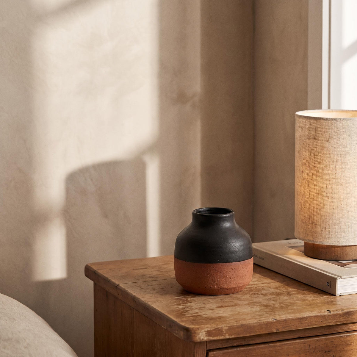Terra vase empty on a bedside table in afternoon light