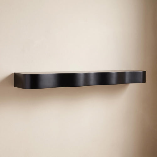Bruko black floating wall shelf with undulating front edge, empty, on a warm neutral wall