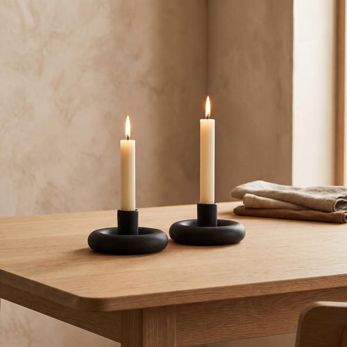 Anel holders on a dining table with two lit cream tapers